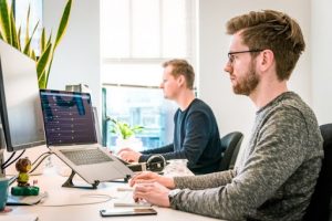 Two employees analyzing data on a computer as part of a security compliance audit.