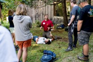 Groupe en situation d’apprentissage lors d’une formation TECC, avec démonstration de prise en charge d’une victime en extérieur.